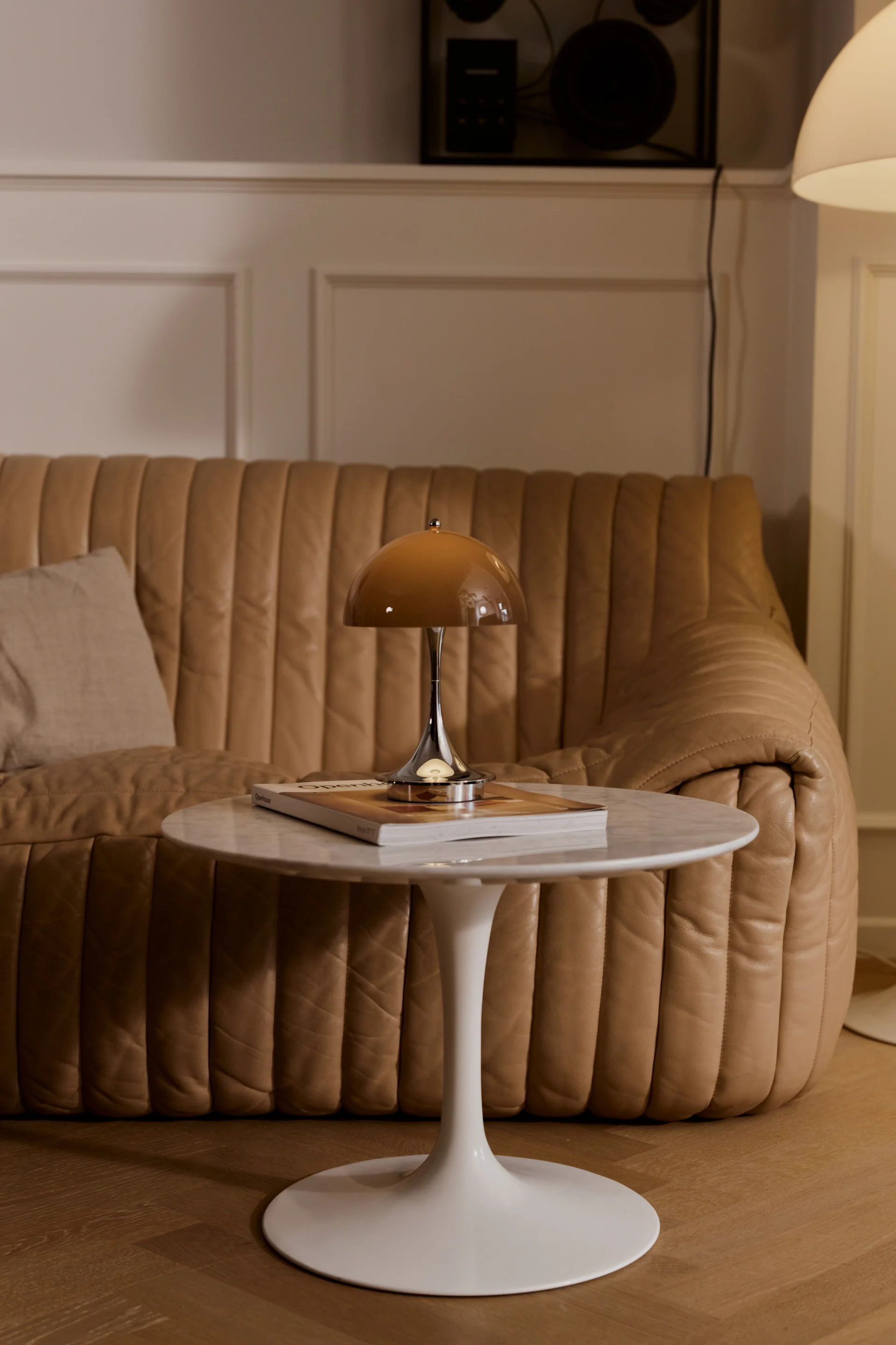 A brown Panthella table lamp placed on a side table complements the sofa in the background, with both featured in the warm kombucha shade that defines the interior colour trends of 2026.