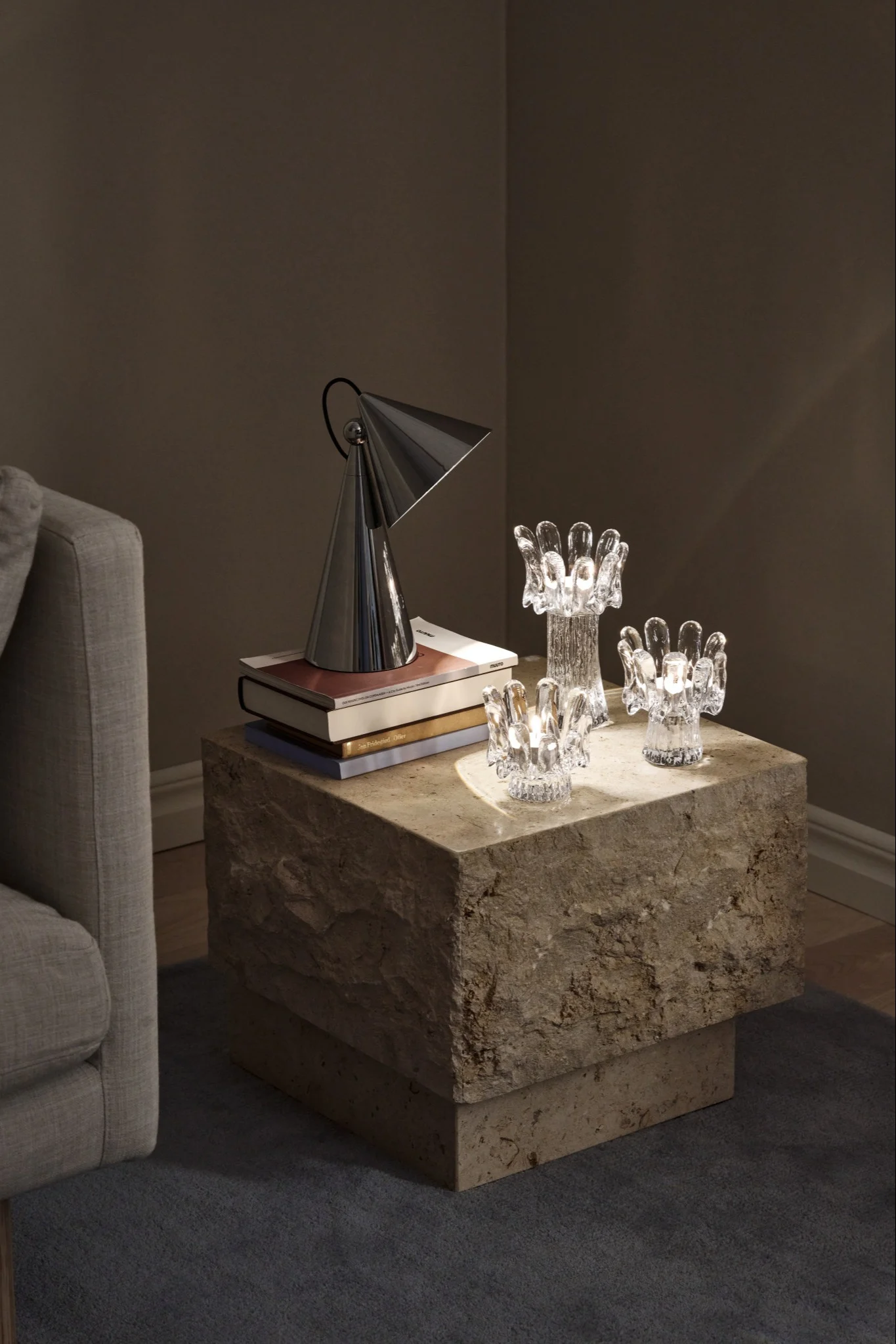 A dark setting illuminated by three glass candle holders shaped like sunflowers, placed on a stone table,  a stylish hint at the interior design trends of 2026.